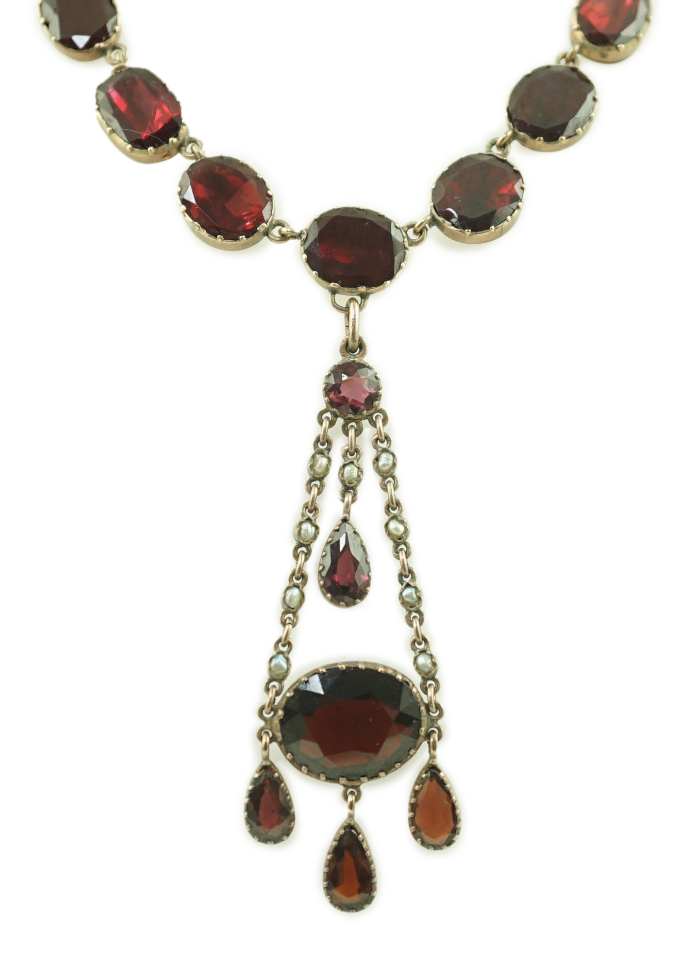 An early 19th century gold, and thirty five graduated foil backed garnet set necklace, with later garnet and seed pearl set drop
